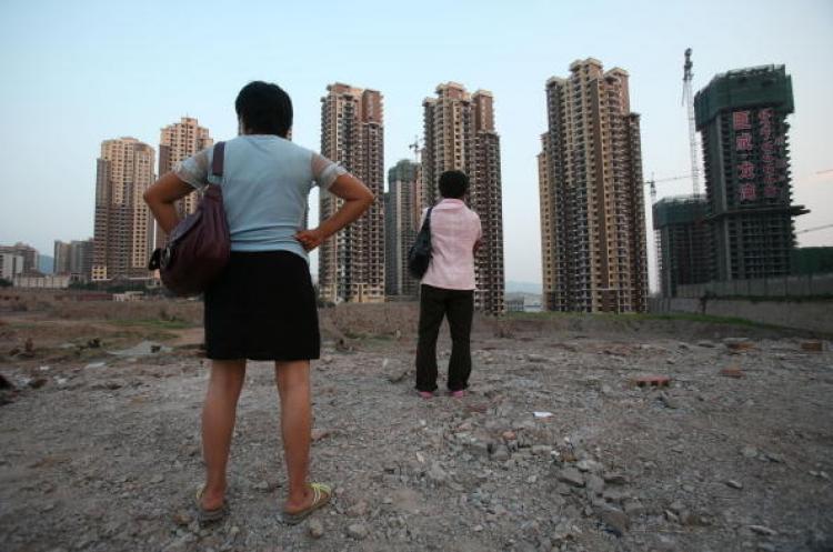 The Chinese real estate market is about to have a new tax added. Pictured, two women in Chongqing are looking at apartment buildings under construction. (AFP/Getty Images) The Chinese real estate market is about to have a new tax added. Pictured, two women in Chongqing are looking at apartment buildings under construction. (AFP/Getty Images)