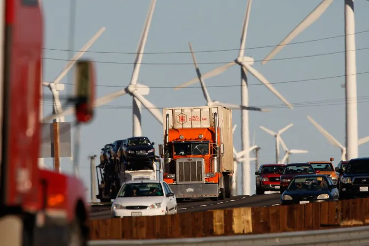 Emissions-producing cars and trucks pass a wind farm along the California freeway. Americans are deeply polarized in their beliefs about climate change, and researchers want to know why. (David McNew/Getty Images) 