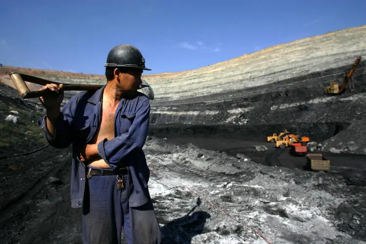 A coal miner walks on coal seams in an open pit coal mine in Chifeng of Inner Mongolia Autonomous Region, China on Aug. 19, 2006. (China Photos/Getty Images)