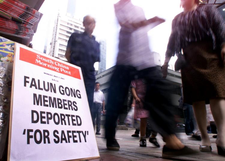 People walk past a newspaper headline announcing the deportation of two Falun Gong practitioners on a street in Hong Kong on May 7, 2001. (Peter Parks/AFP/Getty Images) People walk past a newspaper headline announcing the deportation of two Falun Gong practitioners on a street in Hong Kong on May 7, 2001. (Peter Parks/AFP/Getty Images)