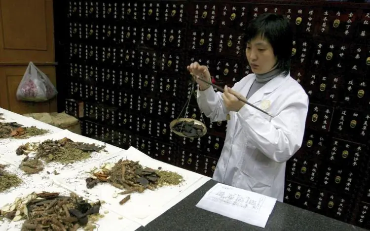 A woman weighs traditional Chinese herbs at a medicine shop in Beijing, China, in November, 2006. (Guang Niu/Getty Images)
