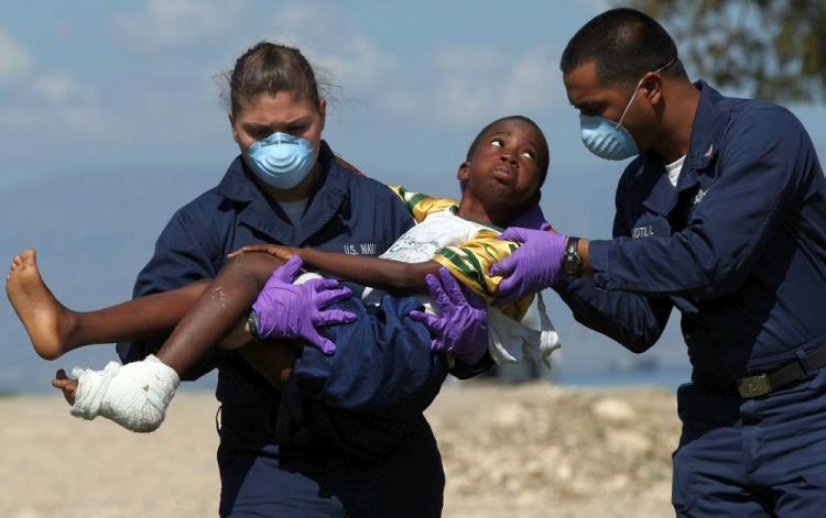 A young Haitian boy injured in last week's devastating earthquake is carried by two members of the U.S. Navy to a waiting medical evacuation helicopter for treatment Jan. 21 in Port-au-Prince, Haiti. Aid organizations report shortages and slow mobilization of relief supplies. They say priority aid is being given to the most vulnerable people. (Win McNamee/Getty Images)