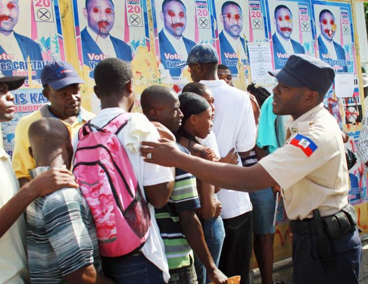 A police officer keeps order, as people stand in line to get their federal identification card, which they will need to be able vote on Nov. 28 in Port-au-Prince, Haiti. Haiti is experiencing a cholera epidemic, and some fear violence in the upcoming elections. Nineteen candidates are running for president, four of whom are calling for the elections to be postponed. (Joe Raedle/Getty Images)