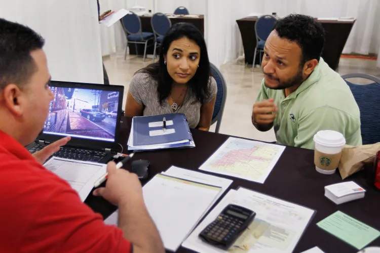 Michelle Ruiz (L) and Nilson Ruiz listen as Wells Fargo home mortgage consultant Michael Carreras in Miami, Fla. (Joe Raedle/Getty Images)
