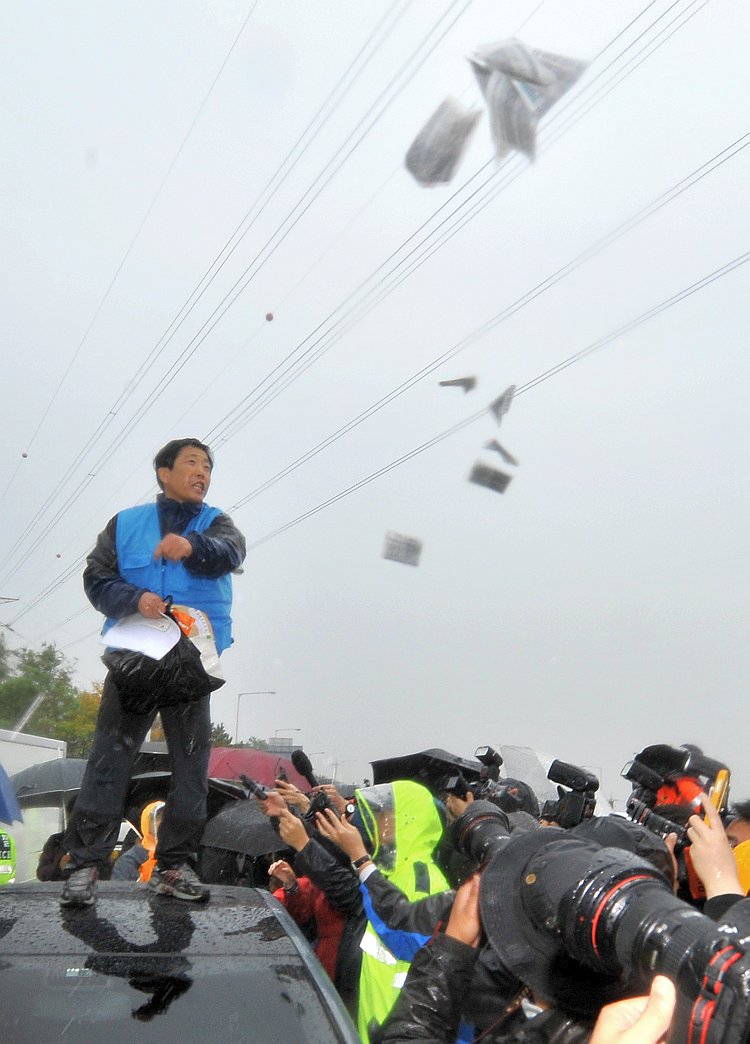 Park Sang Hak, an activist and former defector from North Korea, scatters anti-Pyongyang leaflets on a roadway as police block his planned rally near the tense border in Paju, north of Seoul, on Oct. 22.
