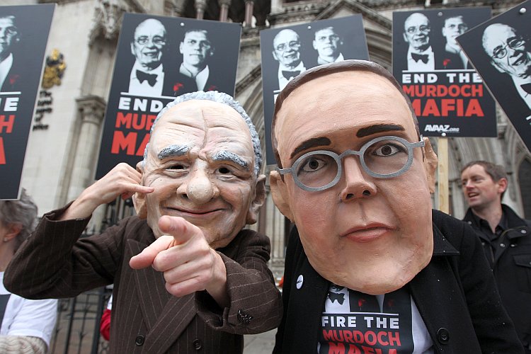 Protesters wearing large Rupert and James Murdoch masks Protesters wearing large Rupert and James Murdoch masks