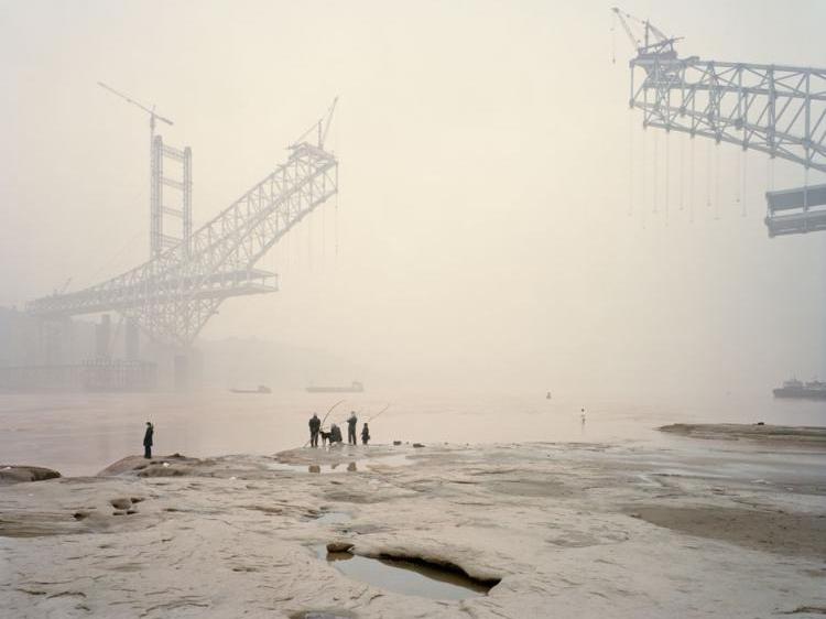 An image in Nadav Kander's book 'Yangtze-The Long River,' of the Chaotianmen Bridge, the world's longest arched bridge, being built over China's Yangtze river. (Courtesy of Hatje Cantz) An image in Nadav Kander's book 'Yangtze-The Long River,' of the Chaotianmen Bridge, the world's longest arched bridge, being built over China's Yangtze river. (Courtesy of Hatje Cantz)