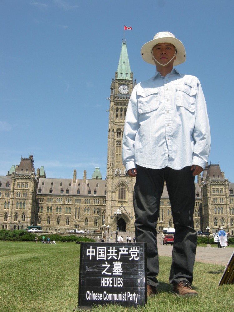 Sun Wujun, an Ottawa resident, poses next to a symbolic tombstone he erected for the Chinese communist party to protest the forced demolition of his family's home in China. (Photo curtesy of Sun Wujun) Sun Wujun, an Ottawa resident, poses next to a symbolic tombstone he erected for the Chinese communist party to protest the forced demolition of his family's home in China. (Photo curtesy of Sun Wujun)