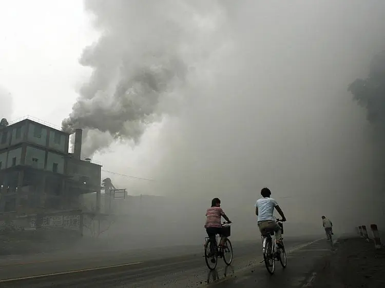 Occupational Hazard: Cyclists pass through thick pollution from a factory in Yutian, Hebei Province, China, in 2006. The surrounding area has a high rate of cancer and death and many villagers are harassed as they try to seek justice. (Peter Parks/AFP/Getty Images)