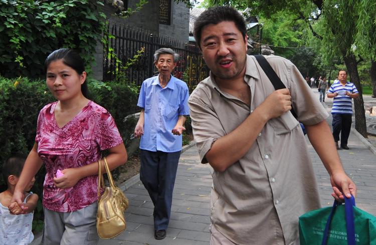 Hai Mingyu (2nd R) walks through a Beijing park chased by plainclothes security personnel (R) despite the Chinese government's promises to allow protests. (Frederic J. Brown/Getty Images)
