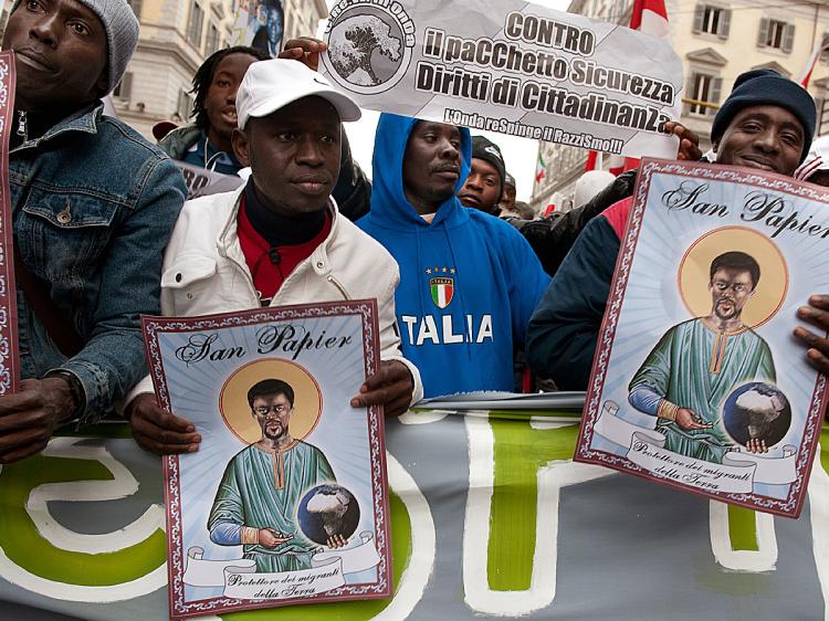 Protesters march in Rome during a demonstration against all sorts of racism. Placards show 'San Papier, the Patron Saint of the migrants of the earth'. (Vincenzo Pinto/AFP/Getty Images) Protesters march in Rome during a demonstration against all sorts of racism. Placards show 'San Papier, the Patron Saint of the migrants of the earth'. (Vincenzo Pinto/AFP/Getty Images)