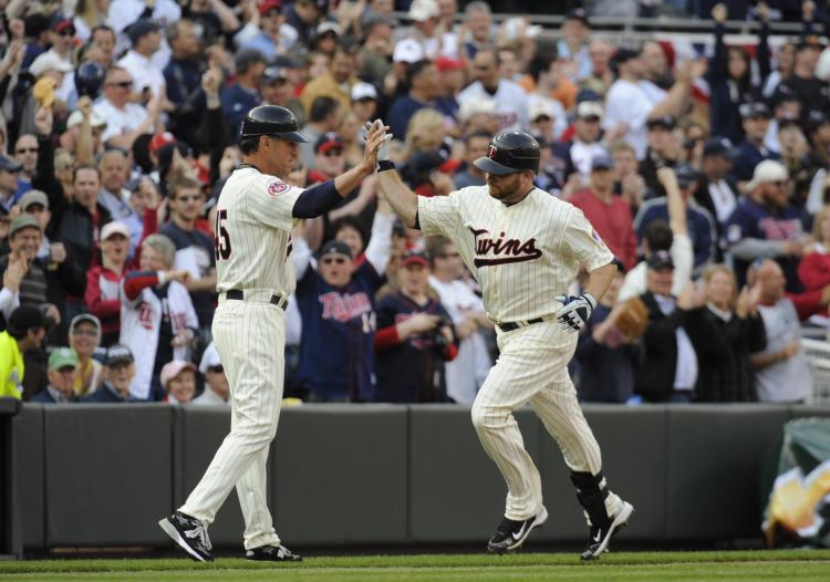 Third base coach Scott Ullger #45 and Jason Kubel #16 of the Minnesota Twins celebrate Kubel hitting the first home run at Target Field in the seventh inning against the Boston Red Sox during the Twins home opener at Target Field in Minneapolis, Minnesota (Hannah Foslien /Getty Images)