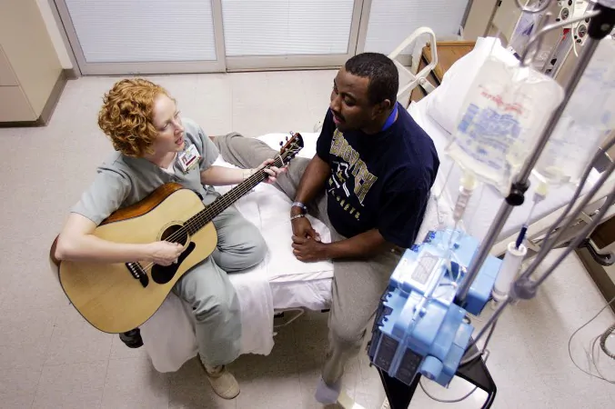A hospital music therapist plays her guitar and sings along with a patient at a hospital in Atlanta in this file photo. Music therapy can be deep and emotionally healing. (AP Photo/Dave Martin)