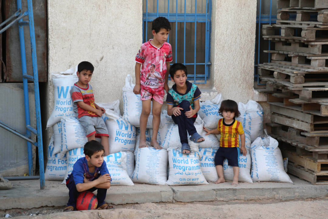 Children sit on World Food Programme sacks at a school that serves as a shelter for internally displaced people in Jamila, Iraq, on June 19. (AP Photo/Karim Kadim)