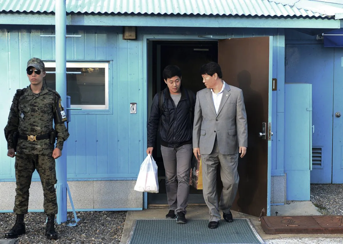 In this photo provided by the South Korean Unification Ministry, South Korean Won Moon Joo, center, who has a permanent resident status in the United States, is escorted by a South Korean official at the border village of Panmunjom in Paju, South Korea, Monday, Oct. 5, 2015. (The South Korean Unification Ministry via AP)