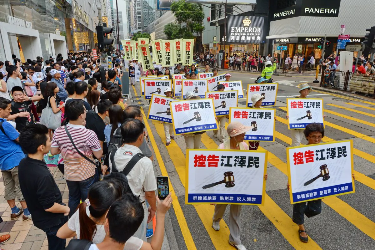 A group of Falun Gong practitioners in the procession hold banners that read “Sue Jiang Zemin” on Oct. 1, 2015. (Epoch Times)