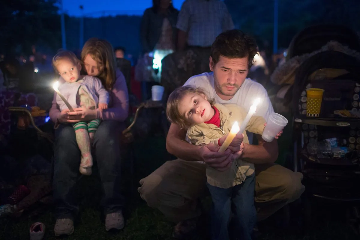Kyle Workman, his wife Christina, and their daughters Pepper (L) and Samantha attend a prayer service and candlelight vigil at River Bend Park to remember the victims of the mass shooting at Umpqua Community College in nearby Roseburg, in Winston, Oregon, on Oct. 3, 2015. On Thursday 26-year-old Chris Harper Mercer went on a shooting rampage at the college killing nine people and wounding another nine before killing himself. Both Kyle and Christina were students at the school. (Scott Olson/Getty Images)