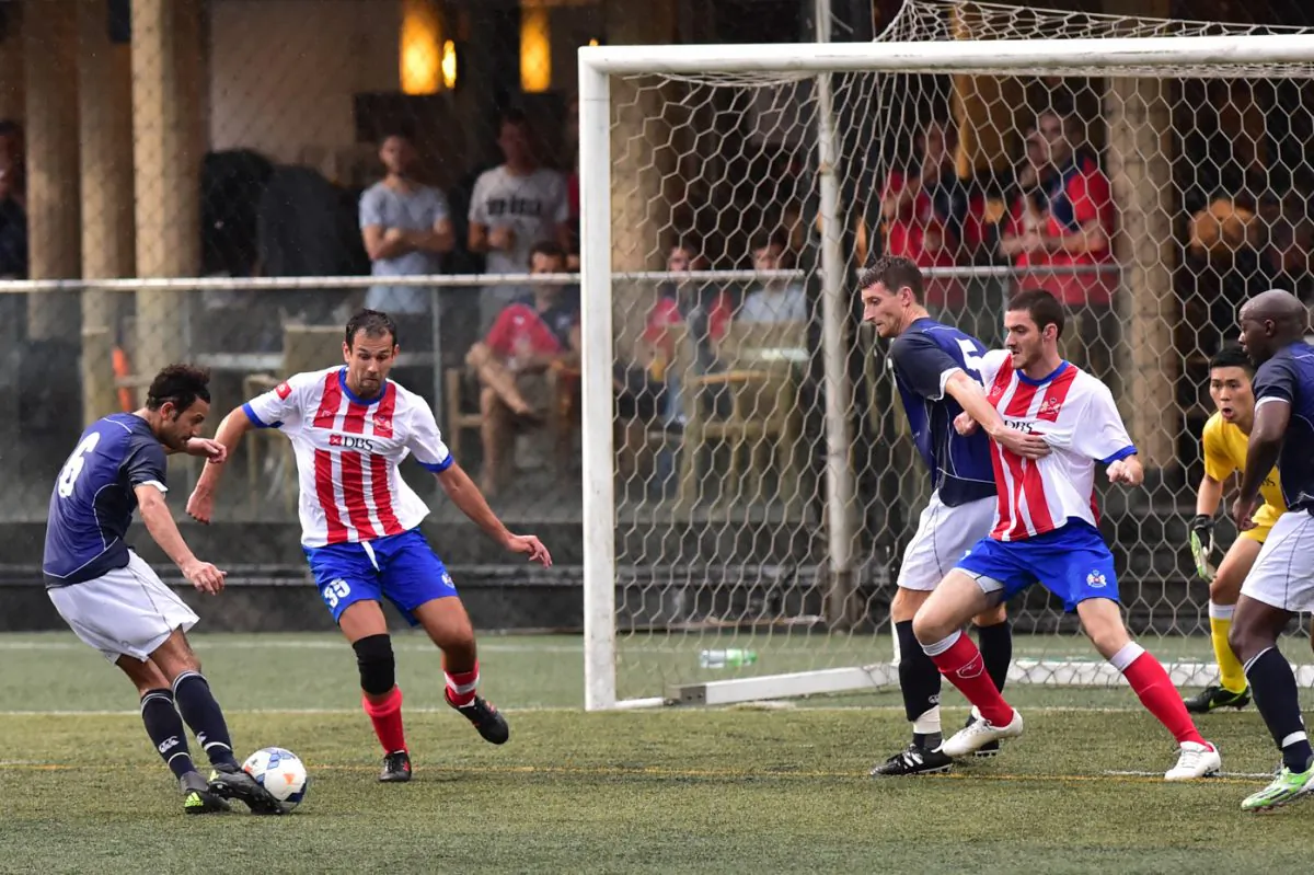 Wanderers Brendan Beni shoots at goal during 3-1 win against The Store House Squadron watched by club mates Mike Thurbon and Abimbolu (Bolu) Olufunwa, and The Storehouse Squadron's Christophe Armand and Bradley Huang during their Yau Yee Division-1 match at Sports Road on Sunday Oct 4. (Bill Cox//Epoch Times)
