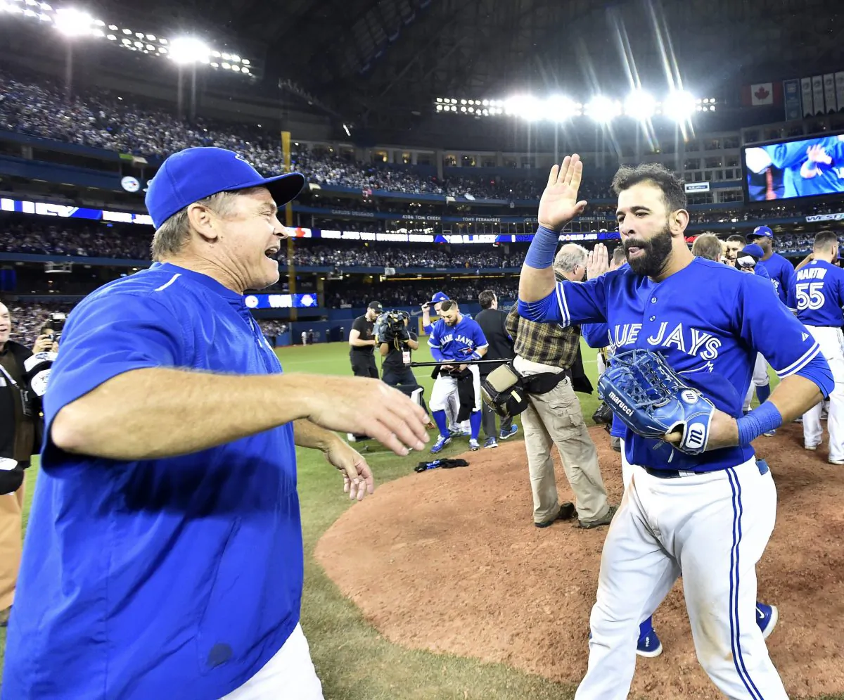 Jose Bautista and John Gibbons celebrate on the field after winning Game 5 over the Texas Rangers in Toronto on Oct. 14, 2015. (The Canadian Press/Nathan Denette)
