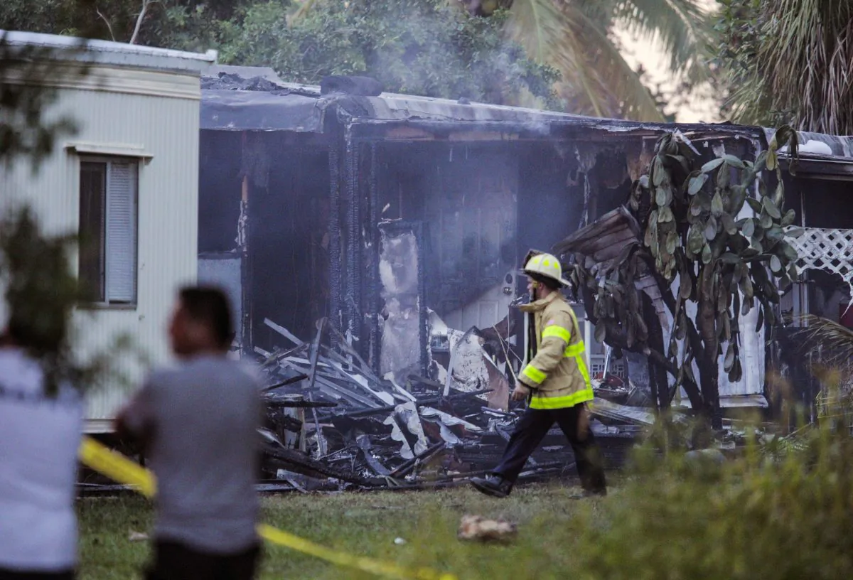 A firefighter walks by a charred mobile home that burned after a small plane crashed in suburban Lake Worth, Fla., Tuesday, Oct. 13, 2015. (Thomas Cordy/Palm Beach Post via AP)