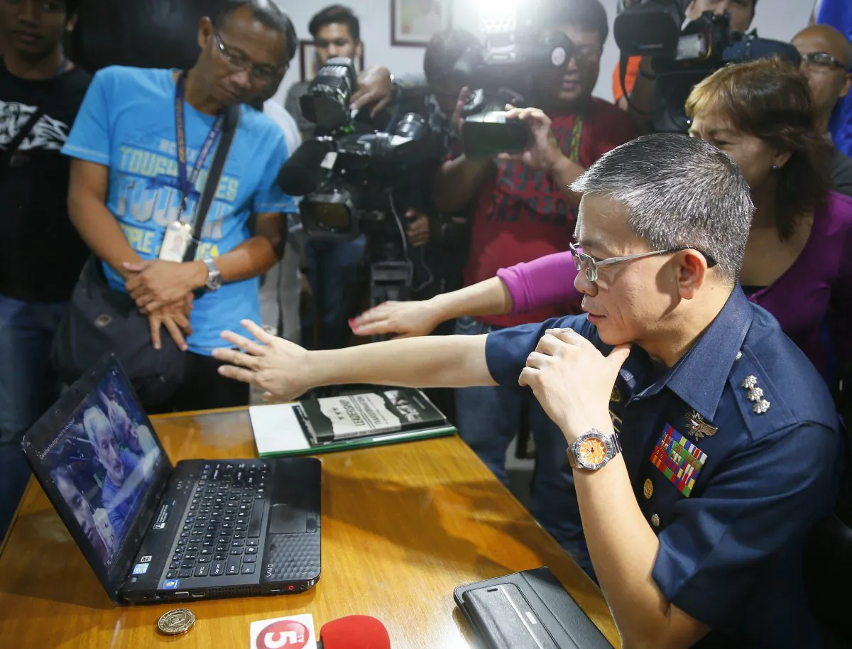 At a press conference in Manila on Oct. 14, 2015, Col. Restituto Padilla, spokesman of the Armed Forces of the Philippines, watches a video of two Canadians, a Norwegian, and a Filipina woman who were abducted last month from a southern Philippines resort. Col. Padilla said the military was trying to verify the video’s authenticity and added that it had rejected the militants’ demands. (AP Photo/Bullit Marquez)
