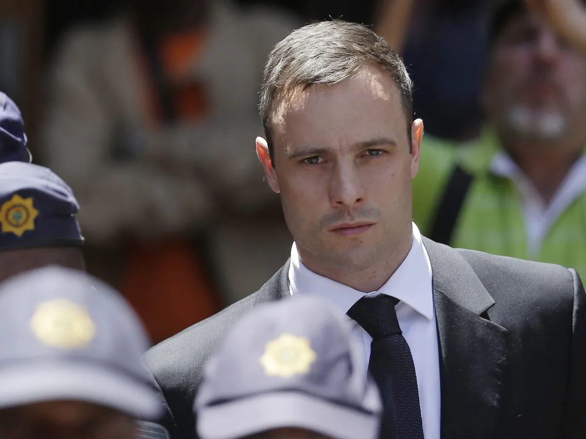 Oscar Pistorius is escorted by police officers as he leaves the high court in Pretoria, South Africa, on Oct. 17, 2014. (AP Photo/Themba Hadebe)