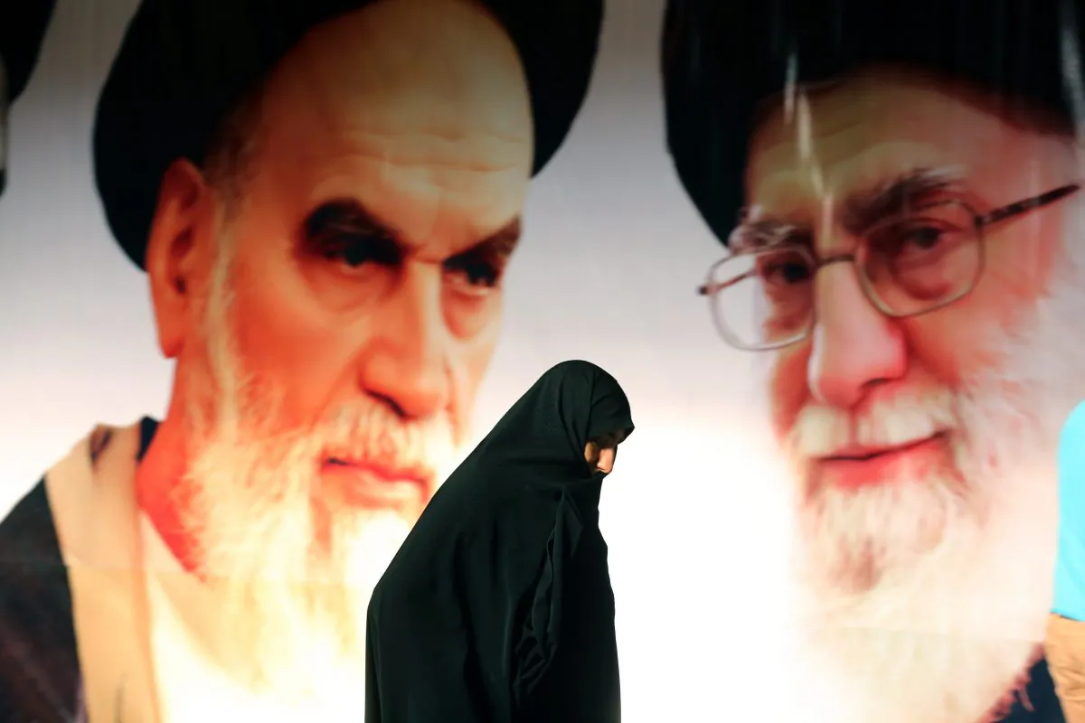 An Iranian woman walks past a big poster showing supreme leader Ayatollah Ali Khamenei (R) and the founder of Iran's Islamic Republic, Ayatollah Ruhollah Khomeini (L), during a ceremony marking the 36th anniversary of his return from exile, at Khomeini's mausoleum in a suburb of Tehran, on Feb. 1, 2015. (Atta Kenare/AFP/Getty Images)