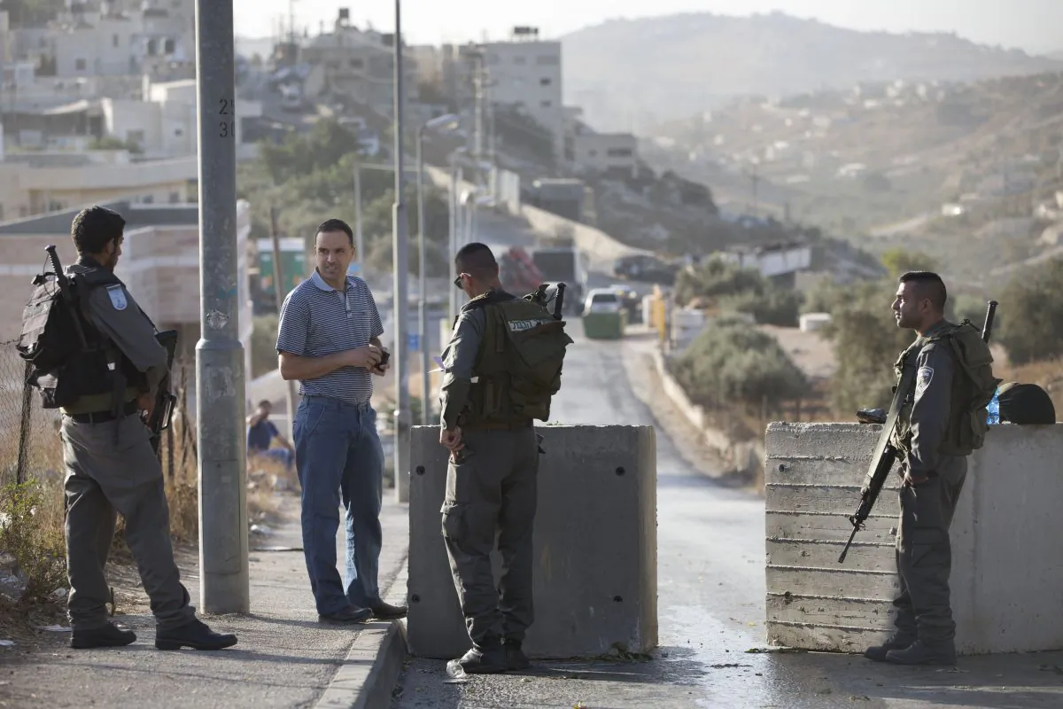 Israeli border police check Palestinian man ID next to newly placed concrete blocks in east Jerusalem neighborhood, Thursday, Oct. 15, 2015. (AP Photo/Oded Balilty)