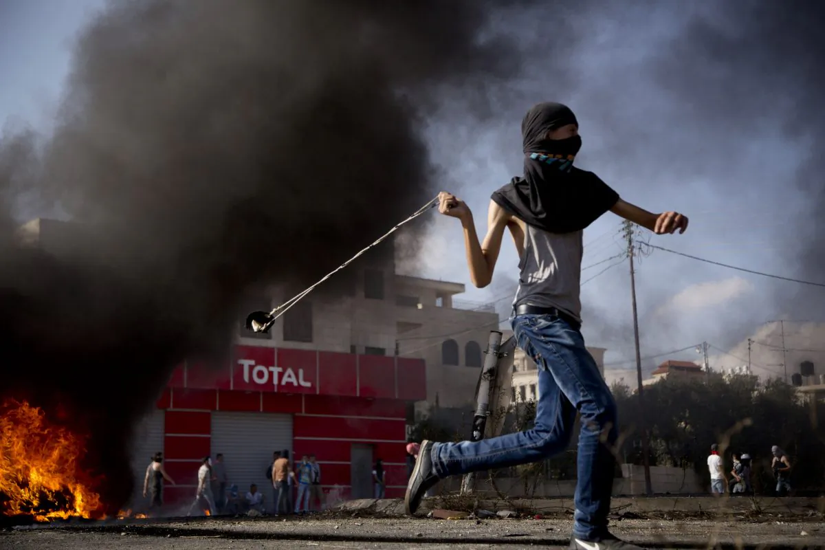 A Palestinian hurls a stone during clashes with Israeli troops near Ramallah, West Bank, on Oct. 14, 2015. Violence quickly spread across Israel and into the West Bank and Gaza Strip after clashes erupted last month over tensions regarding the Al-Aqsa Mosque compound in Jerusalem's Old City. (AP Photo/Majdi Mohammed)