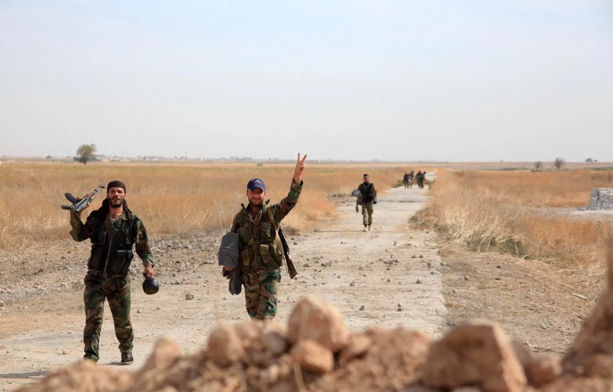 Syrian regime soldiers gesture as they walk down a road in an area around Kweyris military airport, in the eastern Aleppo Province, on Oct. 18, 2015. (George Ourfalian/AFP/Getty Images)