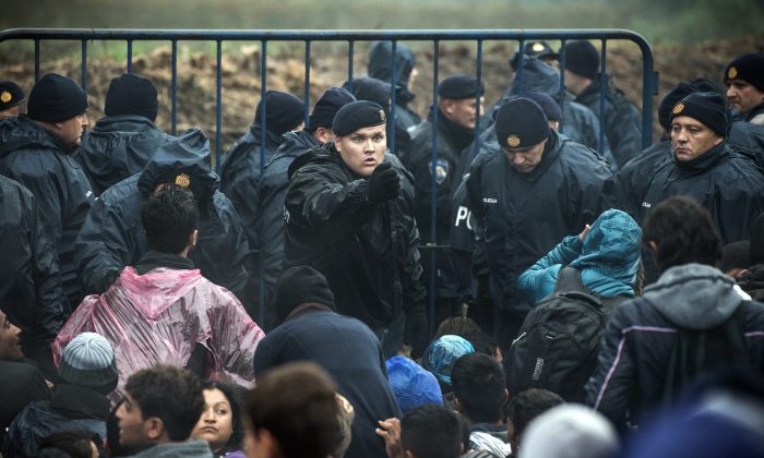 Croatian police officers stand guard as migrants wait to enter Croatia from the Serbia-Croatia border, near the western Serbian village of Berkasovo, on Oct. 19, 2015. (Andrej Isakovic/AFP/Getty Images)