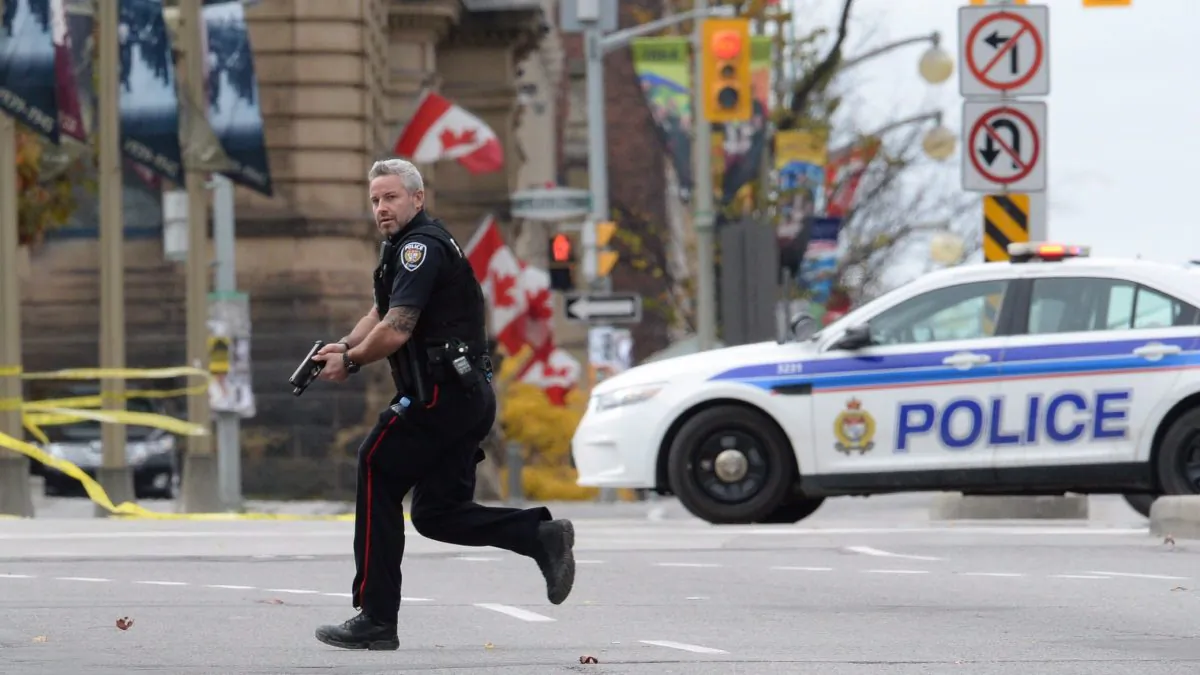 A police officer runs with his weapon drawn in Ottawa on Oct. 22, 2014, during an attack on Parliament Hill by Michael Zehaf Bibeau, who shot Cpl. Nathan Cirillo and injured a security guard before being shot dead by Parliament’s sergeant-at-arms. (The Canadian Press/Sean Kilpatrick)