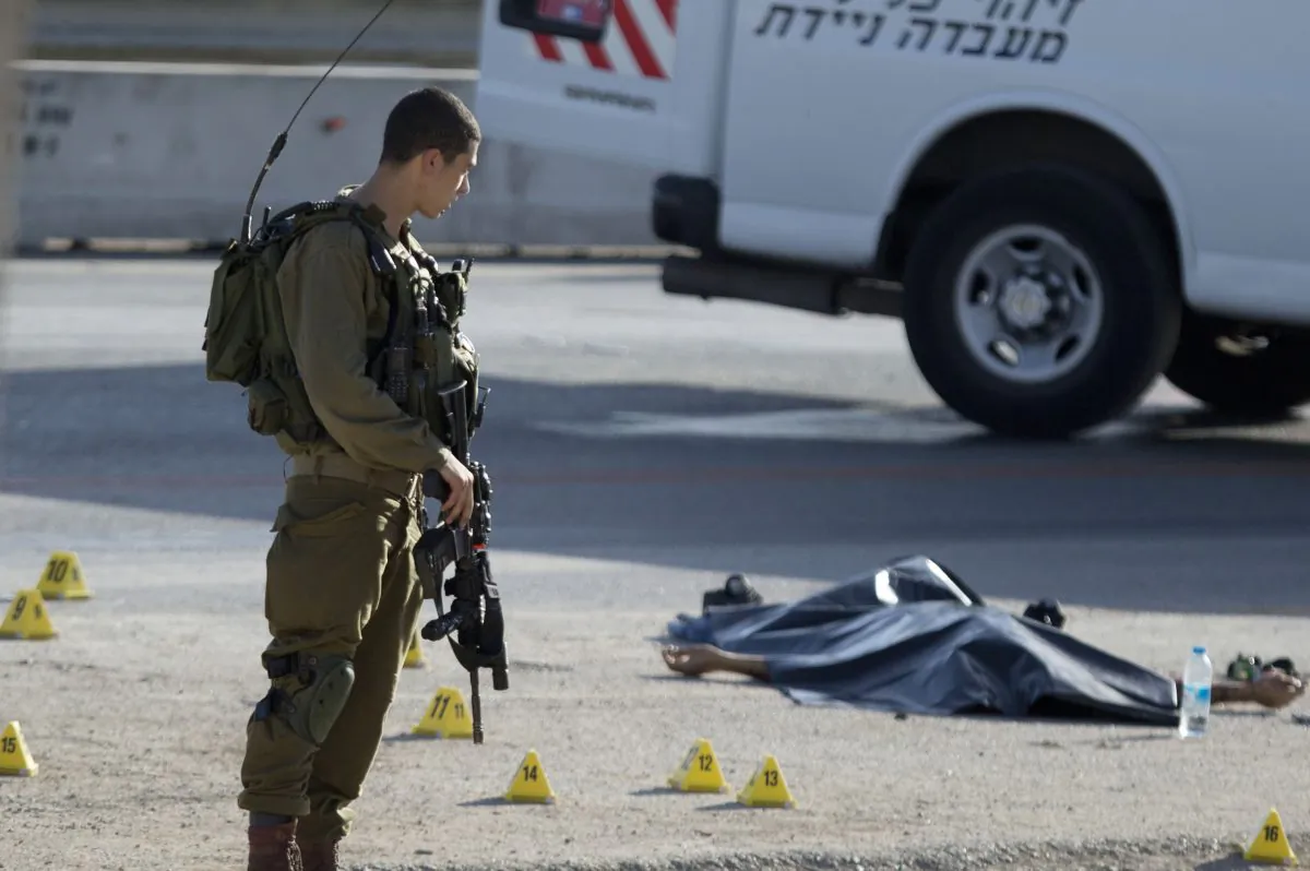 Israeli soldiers stands by the body of a Palestinian man at the scene of a stabbing attack near the West Bank Jewish settlement of Adam, north of Jerusalem, Wednesday, Oct. 21, 2015. (AP Photo/Majdi Mohammed)