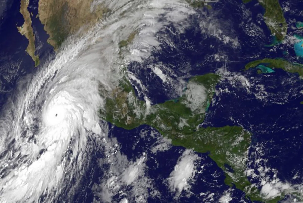 This satellite image taken at 10 a.m.. EDT on Friday, Oct. 23, 2015, and released by the National Oceanic and Atmospheric Administration shows Hurricane Patricia, left, moving over Mexico's Pacific Coast. (NOAA via AP)