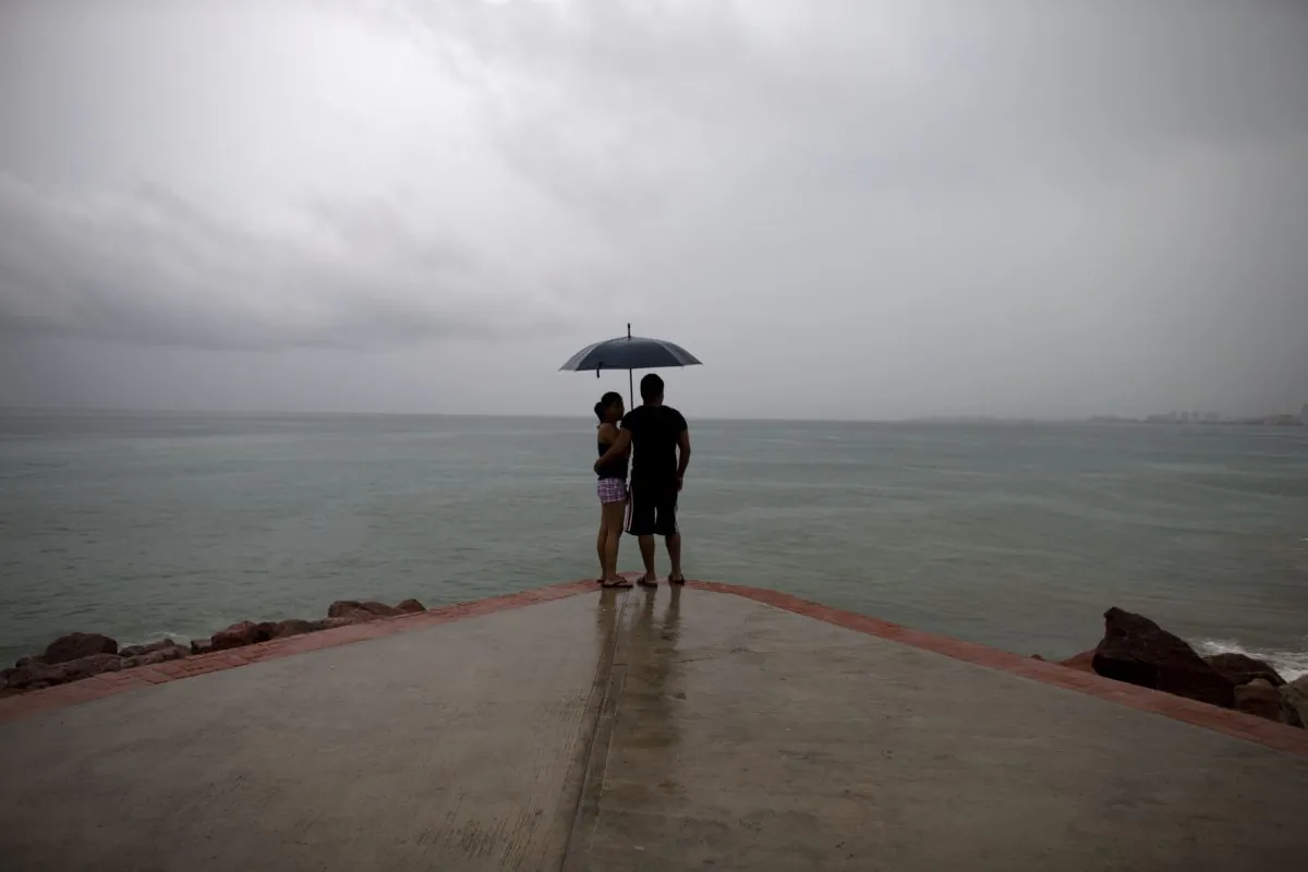 A couple looks out to sea as rainfall increases with the approach of Hurricane Patricia in Puerto Vallarta, Mexico, Friday, Oct. 23, 2015. (AP Photo/Rebecca Blackwell)