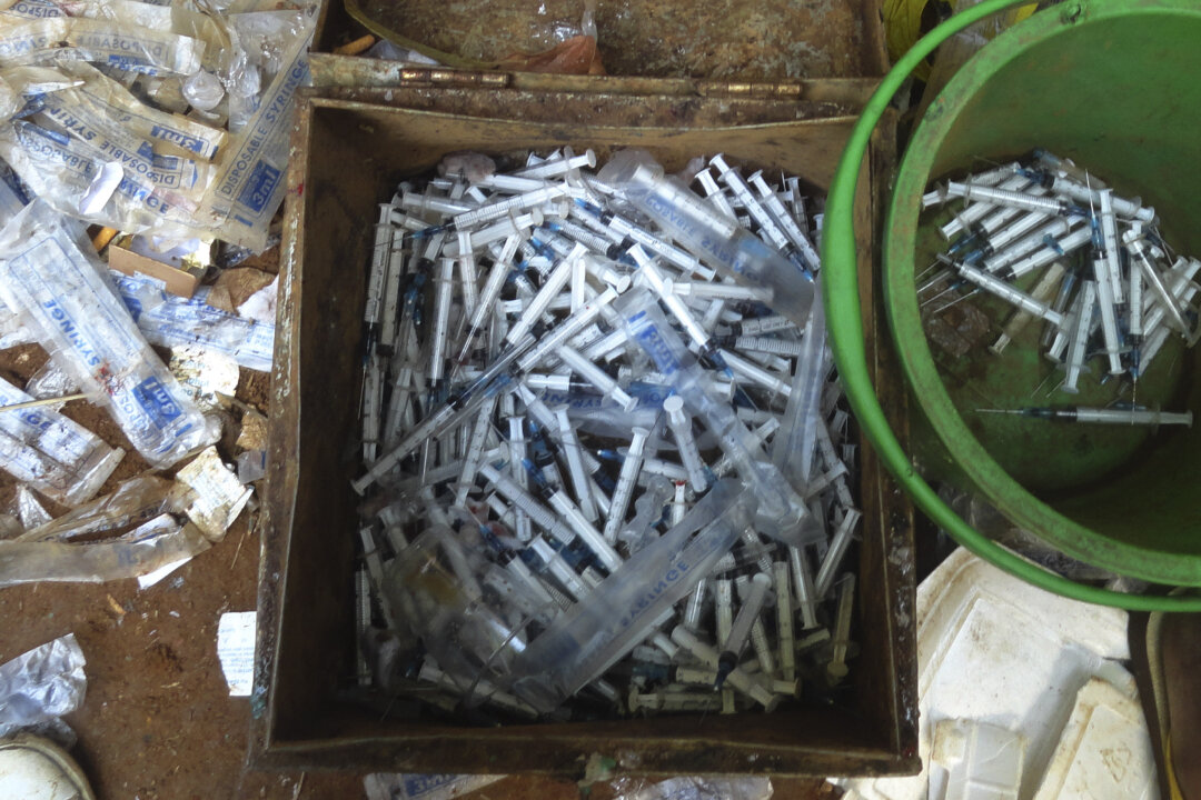 Syringes used to inject drugs are seen in a metal box and a plastic bucket in a tent near the jade mines surrounding Hpakant, in Kachin State, some 600 miles north of Yangon, Burma, in October 2014. (AP Photo)