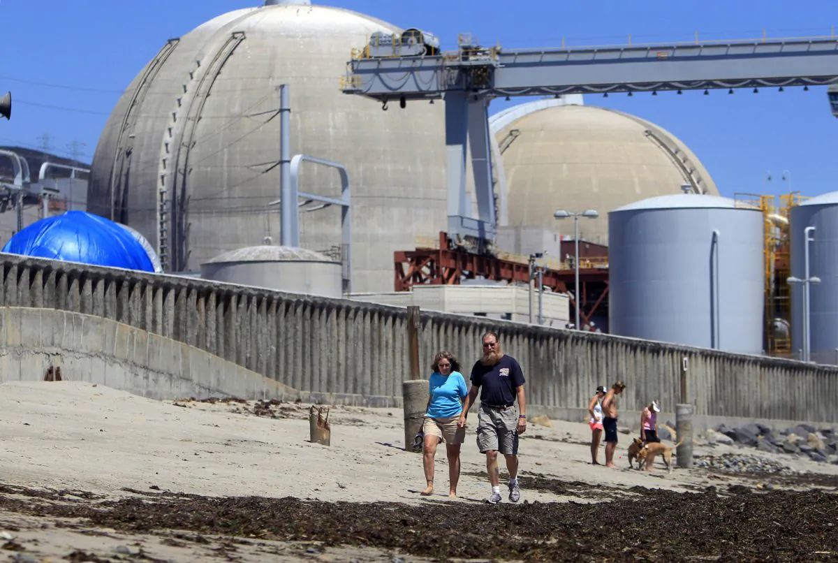 Beachgoers walk on the sand near the San Onofre nuclear power plant in San Clemente, Calif., on June 30, 2011. (AP Photo/Lenny Ignelzi)