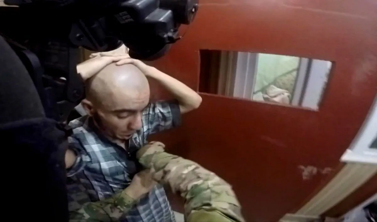 U.S. and Iraqi special forces search prisoners inside a makeshift prison in the town of Huwija, 9 miles (15 km) west of Kirkuk City, Iraq, on Oct. 22, 2015. The Kurdish regional government in northern Iraq released a video Sunday, Oct. 25, 2015 purportedly showing the joint raid of a prison by U.S. and Kurdish peshmerga forces in which they released 70 hostages from the Islamic State groups captivity. The Islamic State flag hangs on the wall. (Kurdistan Regional Security Council via AP)