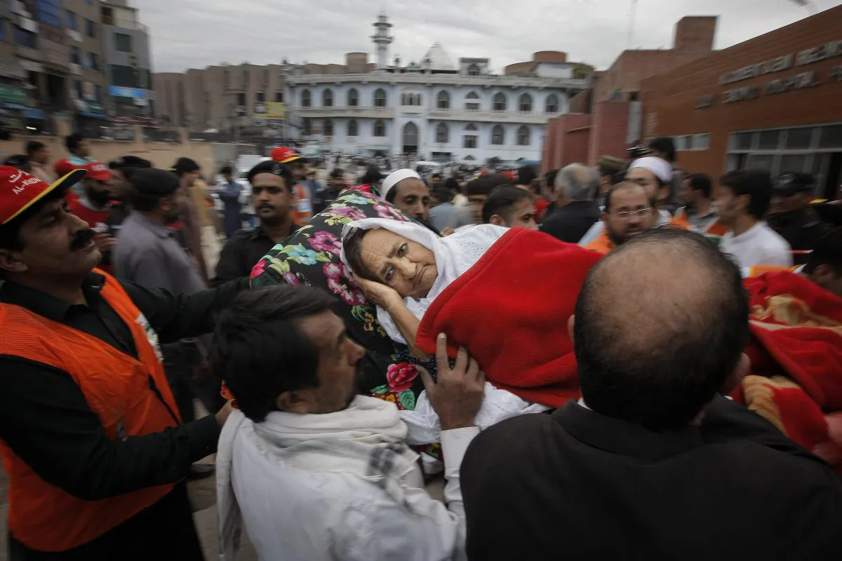 People rush an injured woman to a local hospital in Peshawar, Pakistan, Monday, Oct. 26, 2015. (AP Photo/Mohammad Sajjad)