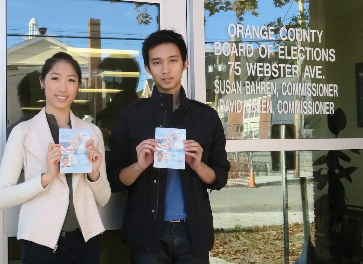 Ashley Wei and Andrew Fung stand outside the Board of Elections holding the U.S. the passports they used to demonstrate their citizenship. (Sue Jones)