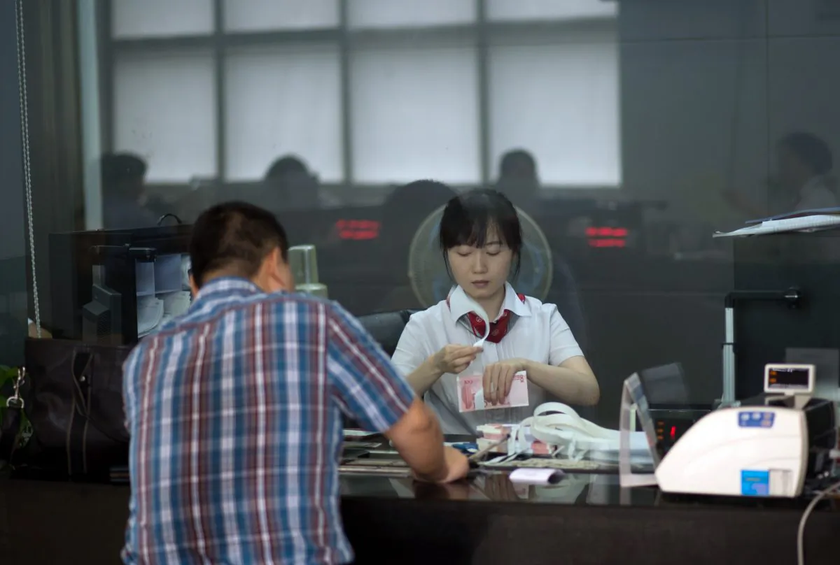 A worker of an bank serves a customer in Shanghai on Sept. 24, 2014.  (JOHANNES EISELE/AFP/Getty Images)