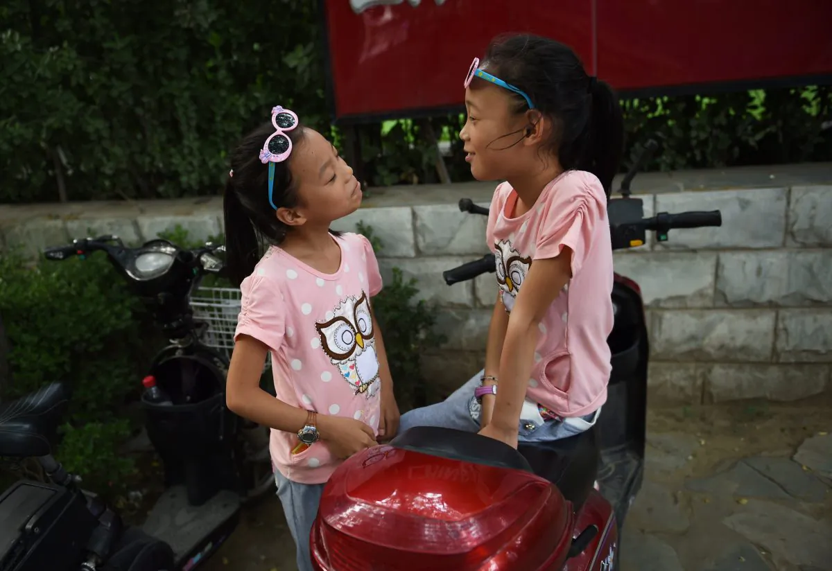 Two sisters play on their parents' electric scooter in Beijing on July 10, 2015. China's one-child policy has been in place for more than three decades, but facing the consequences of a dwindling workforce and a rapidly ageing population, Beijing has been loosening the rules in recent years to encourage more births. (GREG BAKER/AFP/Getty Images)
