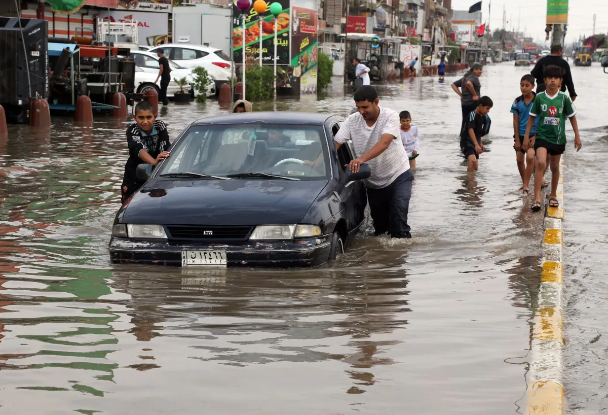Iraqis push a car, submerged in water, as others make their way through a flooded street after heavy rain fell in Baghdad, Iraq, Thursday, Oct. 29, 2015. (AP Photo/Karim Kadim)