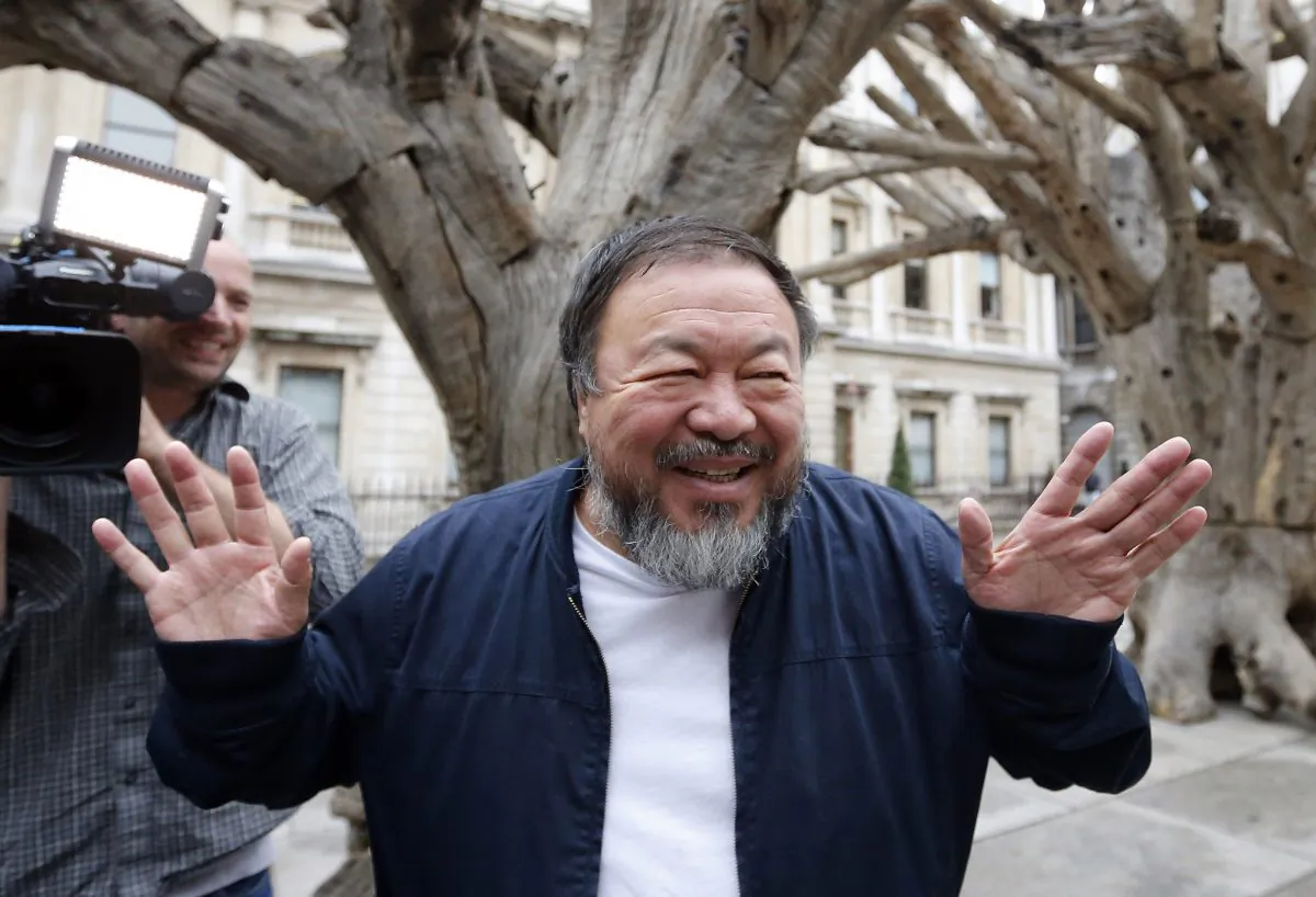 FILE - In this Tuesday, Sept. 15, 2015 file photo Chinese artist Ai Weiwei poses for photographers with one of his pieces at his exhibition at the Royal Academy of Arts in London. Ai Weiwei is taking on Lego, brick by brick. Art galleries around the world are collecting plastic bricks for the artist after the Danish toy company refused to supply Lego for his latest project.(AP Photo/Frank Augstein, File)
