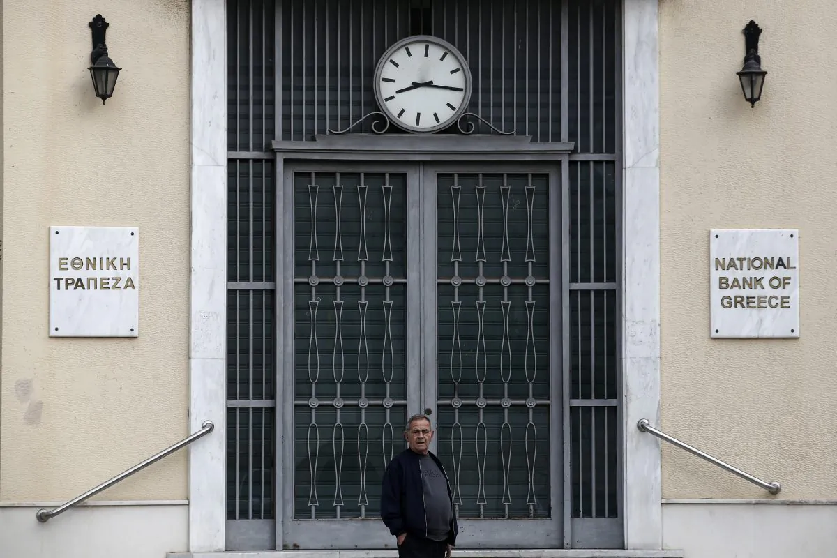 A man stands in front of a National Bank branch in Piraeus, near Athens, Saturday, Oct. 31, 2015. Greece and its bailout creditors remain divided over how to toughen foreclosure laws, according European Union officials, though the overall talks on getting the country the next batch of loans are on track. (AP Photo/Yorgos Karahalis)