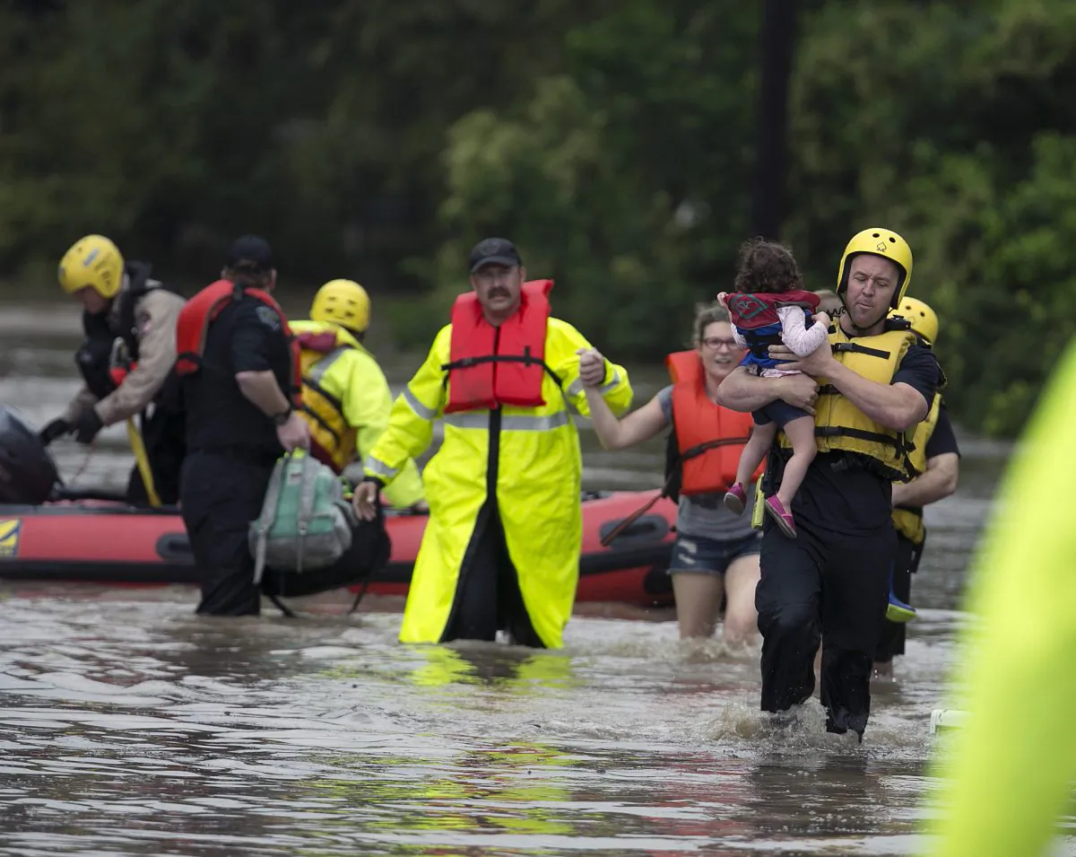 Rescue workers bring out 4-year-old Lana Hauger (R), and Selena Esensee and her 4-year-old son Loki, not seen, after waters rose around Esensee's home leaving them unable to get out in the Bluff Springs neighborhood, on Oct. 30, 2015, in Austin, Texas. A fast-moving storm packing heavy rain and destructive winds overwhelmed rivers and prompted evacuations Friday in the same area of Central Texas that saw devastating spring floods. (Deborah Cannon/Austin American-Statesman via AP)