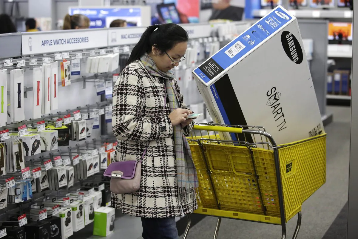 A customer uses her mobile phone as she shops for electronics and other items at a Best Buy on November 27, 2015 in Skokie, Ill., (Photo by Joshua Lott/Getty Images)