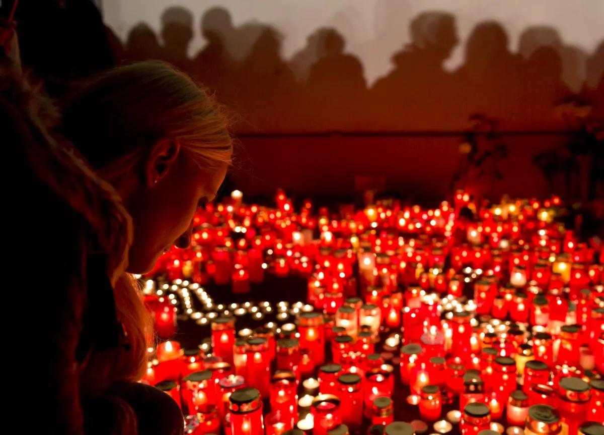 A girl lights candles outside the compound that housed the nightclub where a fire occurred in the early morning hours in Bucharest, Romania, Saturday, Oct. 31, 2015. Hundreds of young people had gone clubbing at the hip Colectiv nightclub Friday night to enjoy a free concert by the Goodbye to Gravity metal band but the evening ended in horror, as the inferno caused a panic that killed tens of people and injured many others. (AP Photo/Vadim Ghirda)