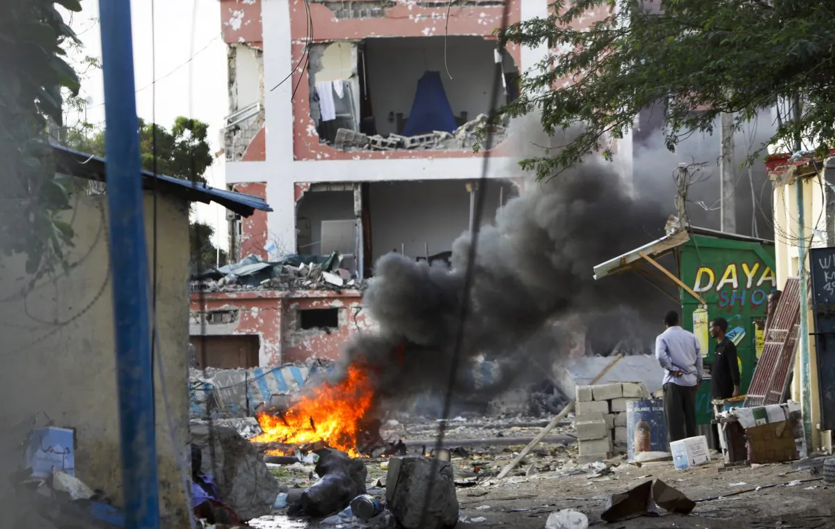 Somali men watch as fires burn amidst the destruction outside the Sahafi Hotel in Mogadishu, Somalia, Sunday, Nov. 1, 2015. A Somali police officer says an explosion followed by heavy gunfire has been heard, thought to have been caused by a suicide car bomb, at the hotel often frequented by Somali government officials and business executives. (AP Photo/Farah Abdi Warsameh)