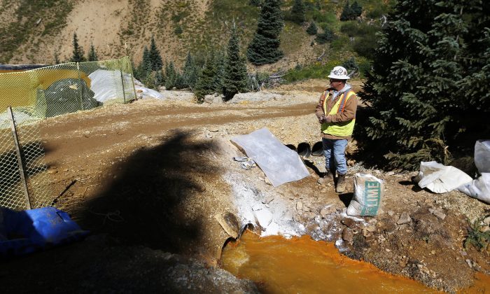 An Environmental Protection Agency contractor keeps a bag of lime on hand to correct the PH of mine wastewater flowing into a series of sediment retention ponds, part of danger mitigation in the aftermath of the blowout at the site of the Gold King Mine outside Silverton, Colo., on Aug. 14, 2015. (AP Photo/Brennan Linsley)